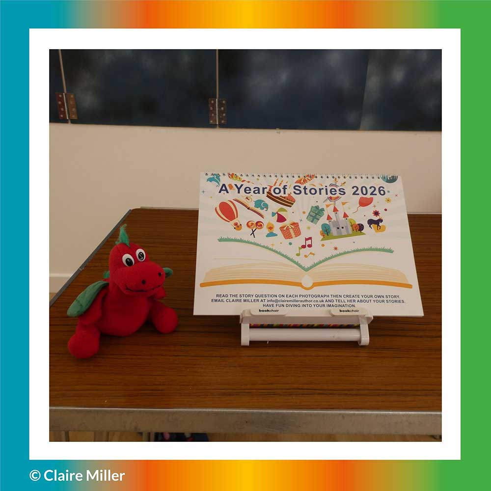 This is a photograph of Claire Miller Story Creator's Story Creating Calendar, called A Year of Stories 2026, on a table, with Rory the story loving dragon, sitting beside it. 