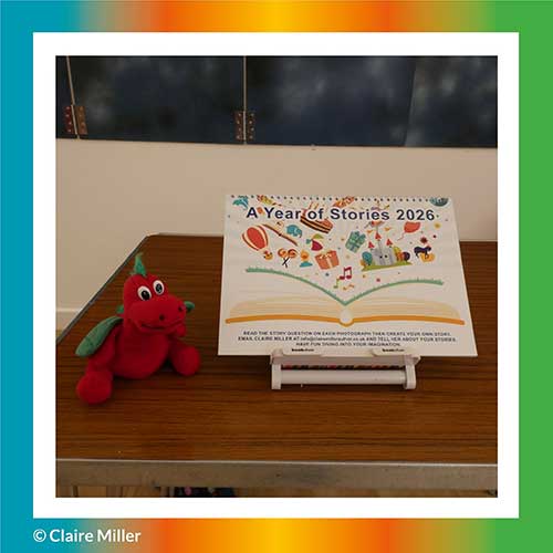 This is a photograph of Claire Miller Story Creator's Story Creating Calendar, called A Year of Stories 2026, on a table, with Rory the story loving dragon, sitting beside it. 